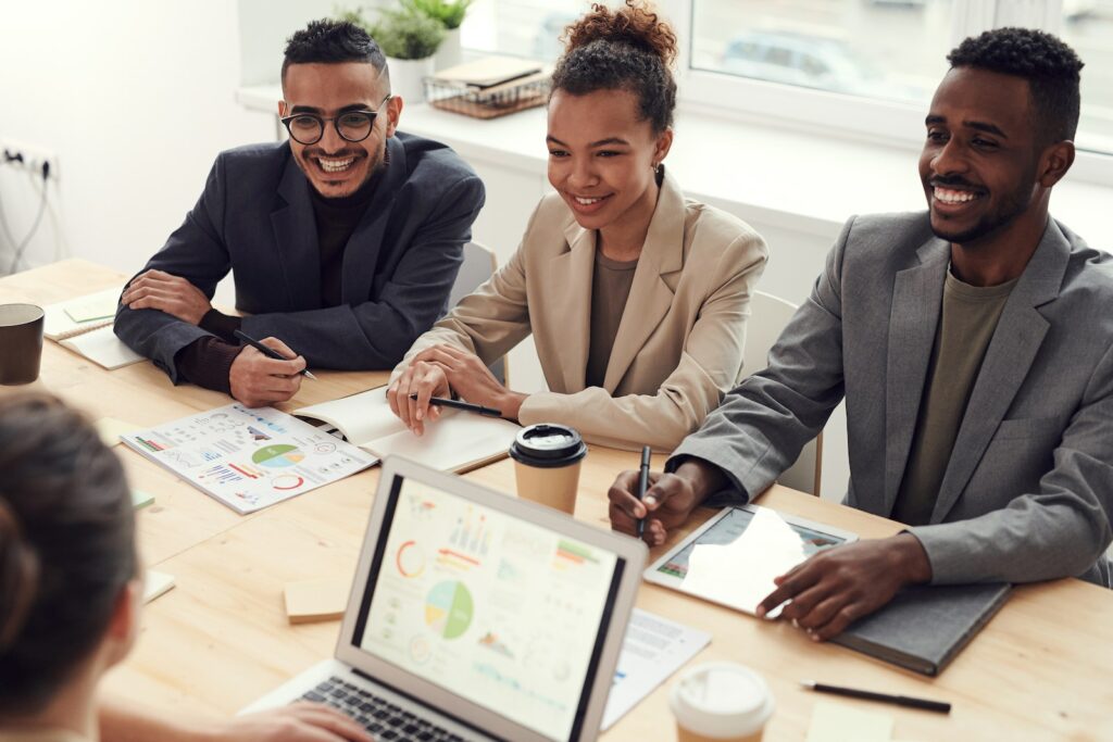 Photo of Three People Smiling While Having a Meeting